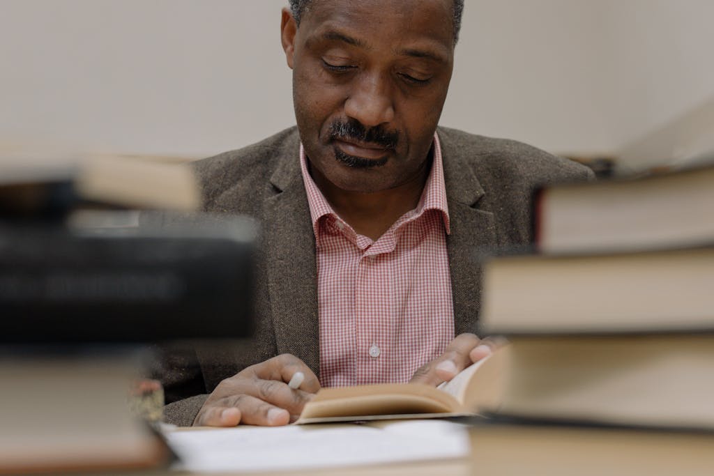 A thoughtful man reading in a library surrounded by books, symbolizing wisdom.